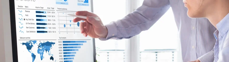 A business man in a shirt pointing at a screen with data and graphs